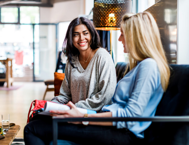 Two female friends sitting side by side at a coffee shop
